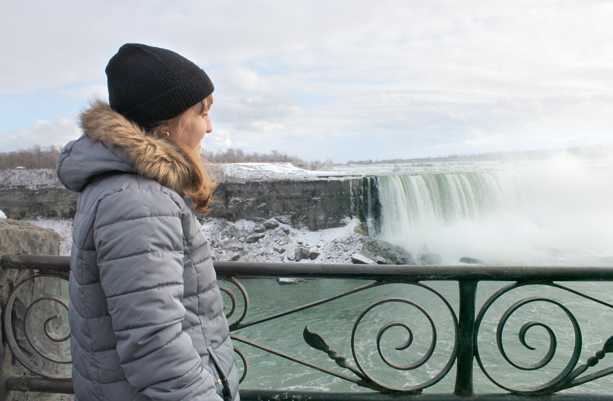 Woman looks out at Niagara Falls in winter time